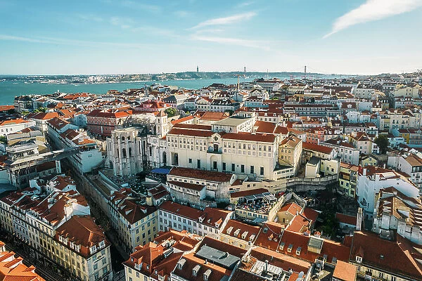 Aerial drone view of Carmo Church and surrounding historic neighbourhood in Chiado, with Tagus River and 25 April Bridge visible, Lisbon, Portugal, Europe