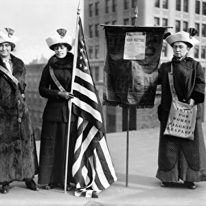 SUFFRAGETTES, c1910. Three women photographed on a Brooklyn rooftop before a demonstration for womens right to vote. One woman holds a poster for the Womens Suffrage Party announcing a mass meeting at the Brooklyn Academy of Music. Photograph, c1910