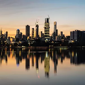 The reflections of the melbourne city skyline at dusk in the still water of albert park